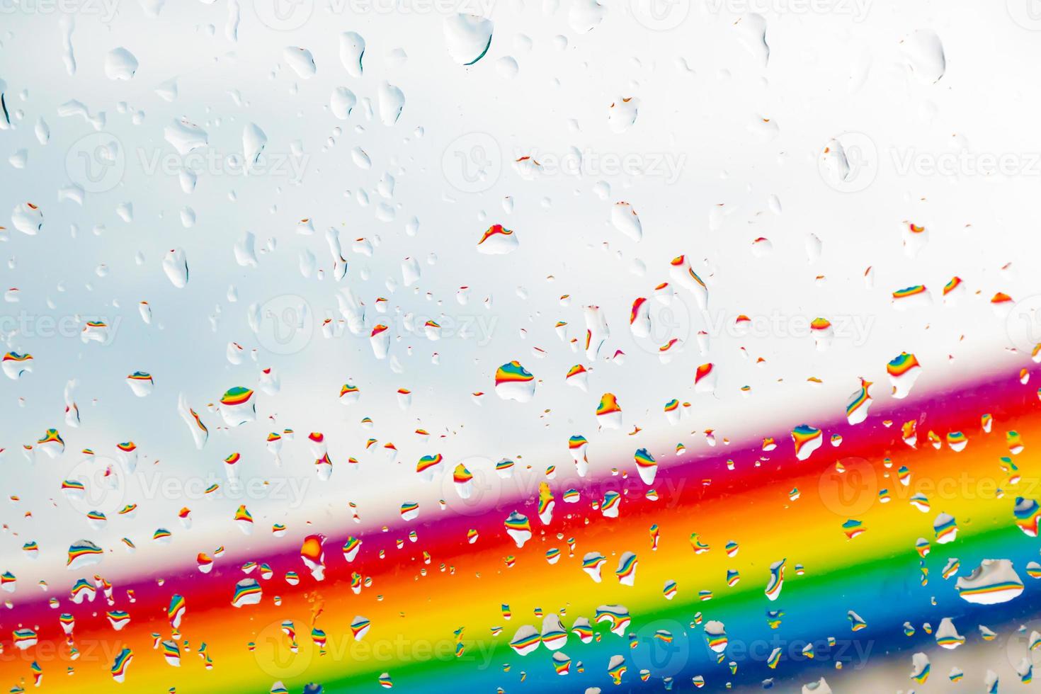 A rainbow behind a glass windows with water drops, Point of view, from behind the glass with drops. photo