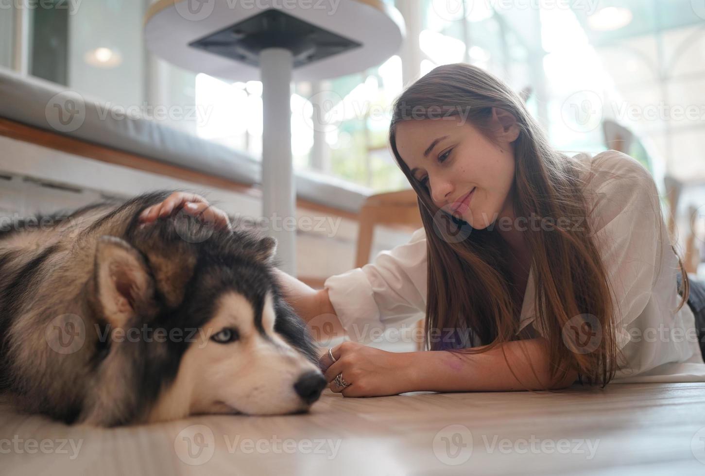 Girl Pet owner hugging with dog puppy. Happy Human female and cute funny dog lying on floor together photo