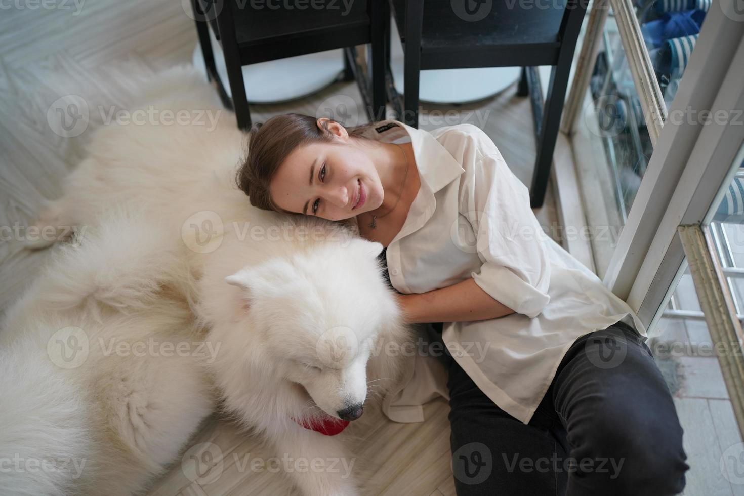 dueña de una mascota abrazándose con un cachorro de perro. feliz mujer humana y lindo perro divertido tirados en el suelo juntos foto