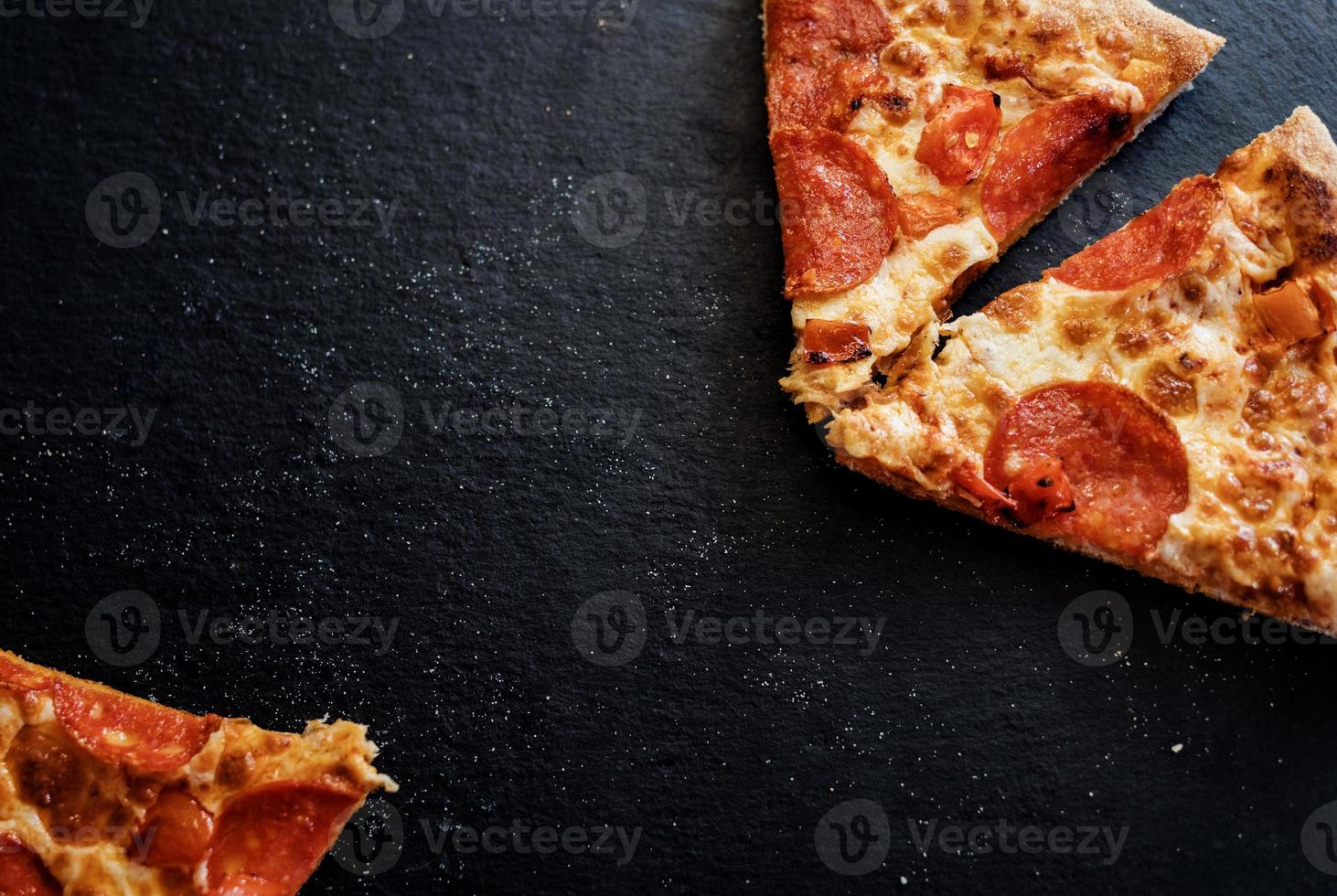 pizza de pepperoni en tablero oscuro foto