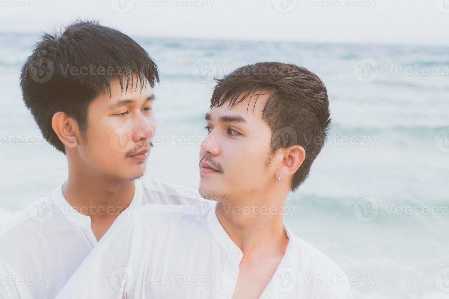 Homosexual portrait young asian couple standing hug and look together on beach in summer, asia gay going tourism for leisure and relax with romantic and happy in vacation at sea, LGBT legal concept. photo