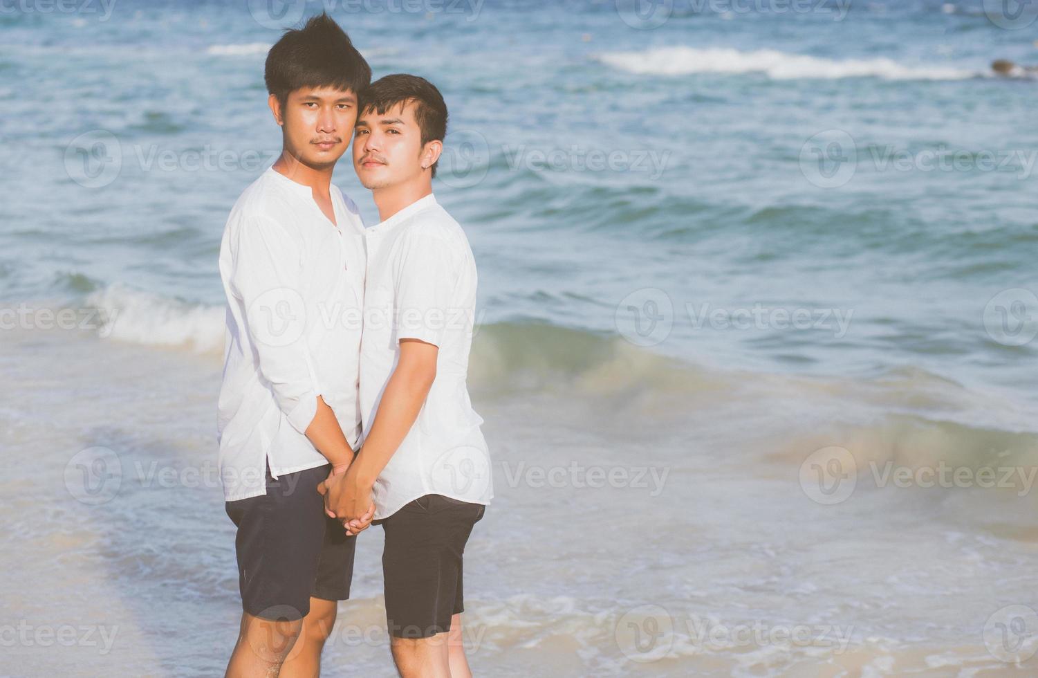 Homosexual portrait young asian couple standing together on beach in summer, asia gay holding hands going sea for leisure and relax with romantic and happy in vacation at sea, LGBT with legal concept. photo