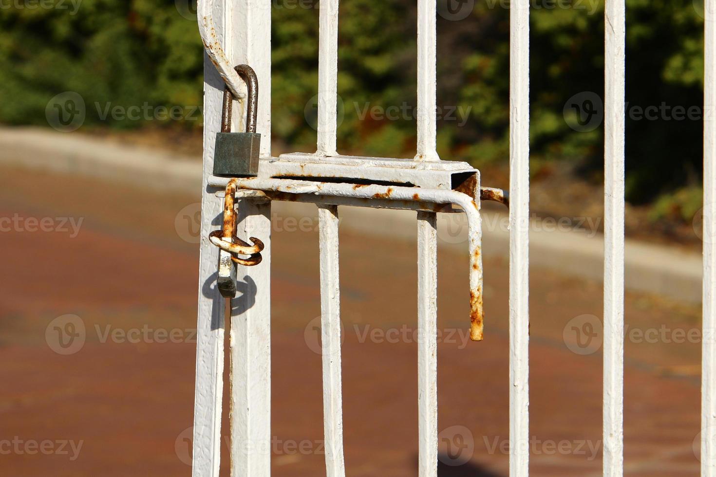 An iron padlock hangs on a closed gate photo
