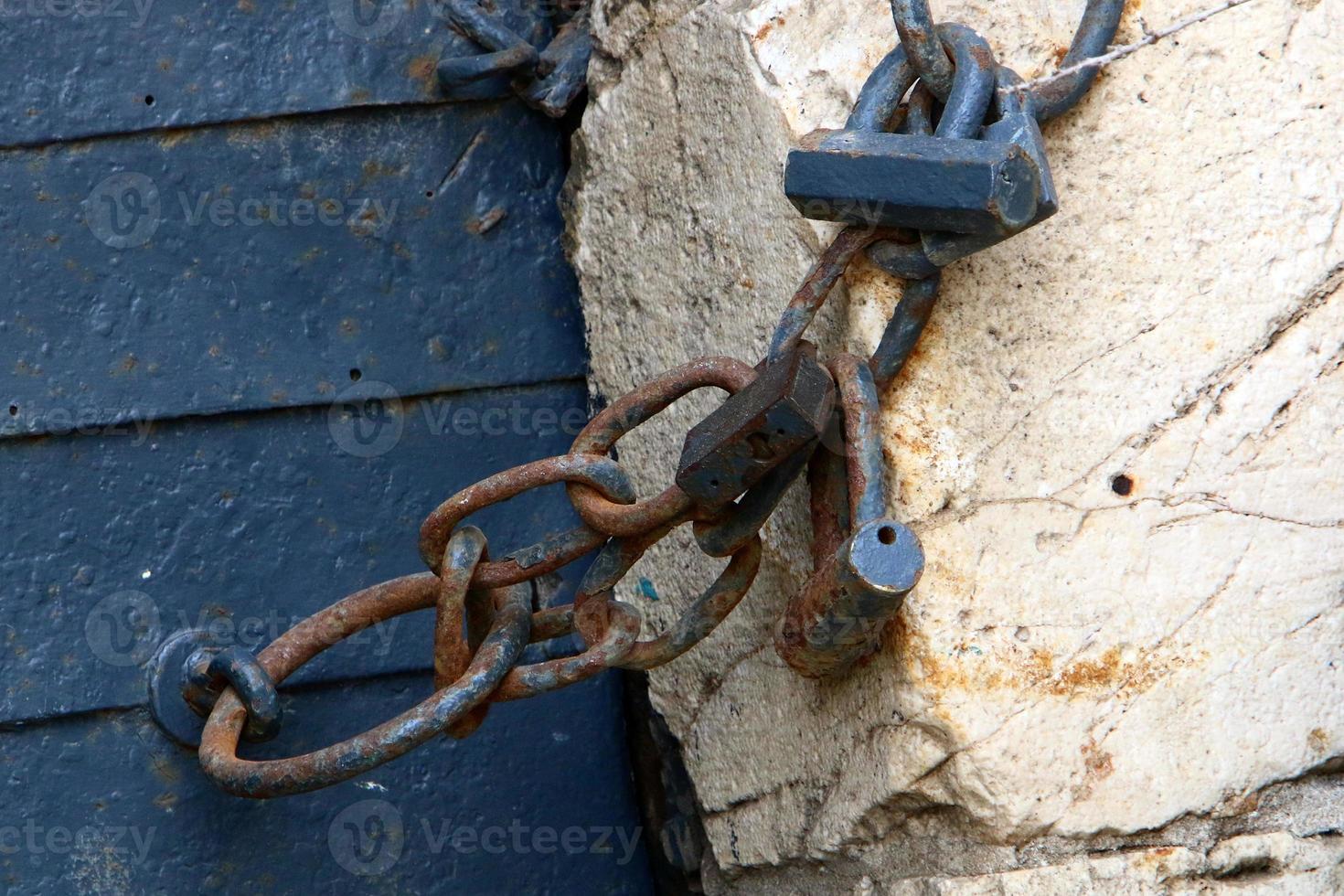 An iron padlock hangs on a closed gate photo