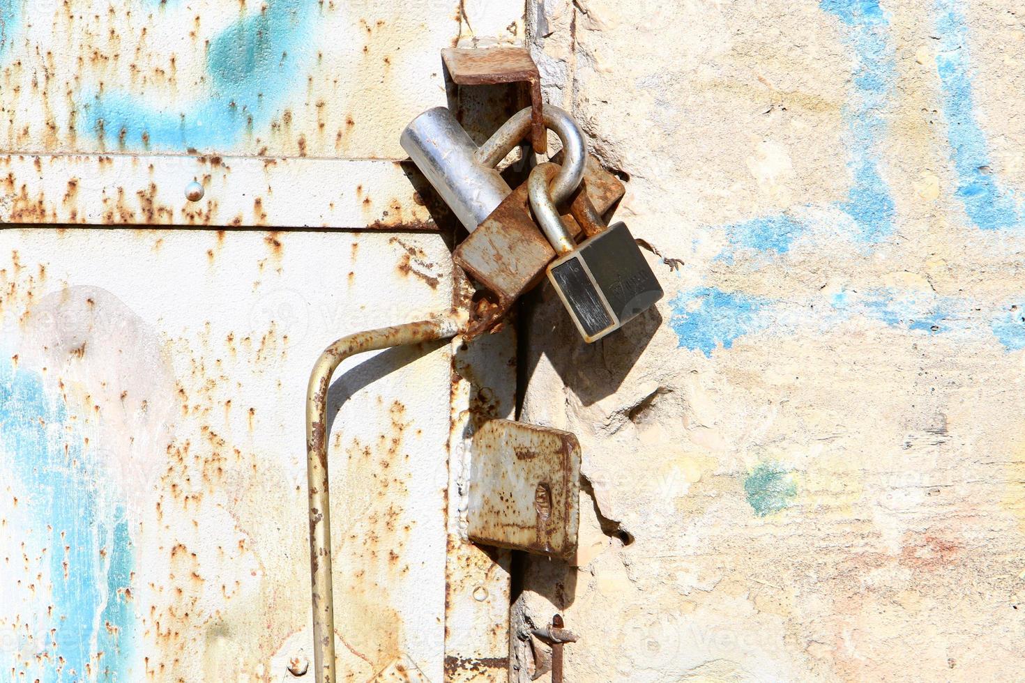 An iron padlock hangs on a closed gate photo