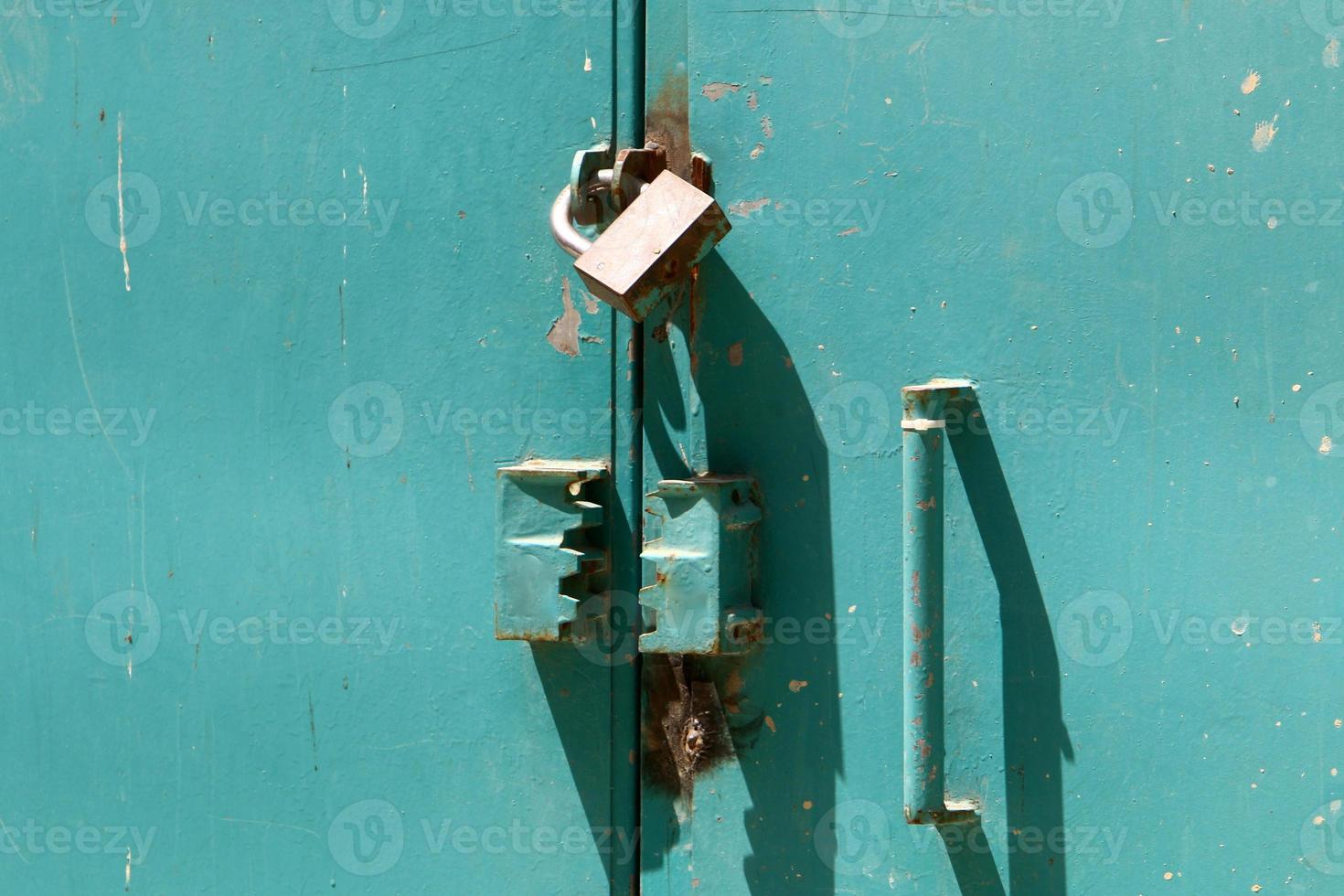 An iron padlock hangs on a closed gate photo