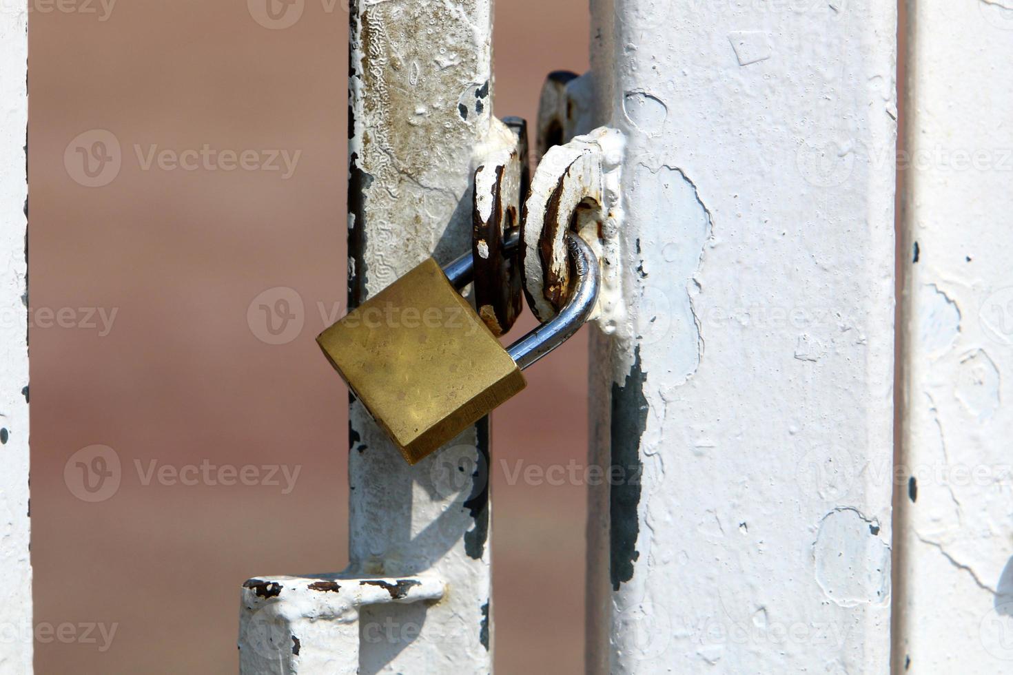 An iron padlock hangs on a closed gate photo