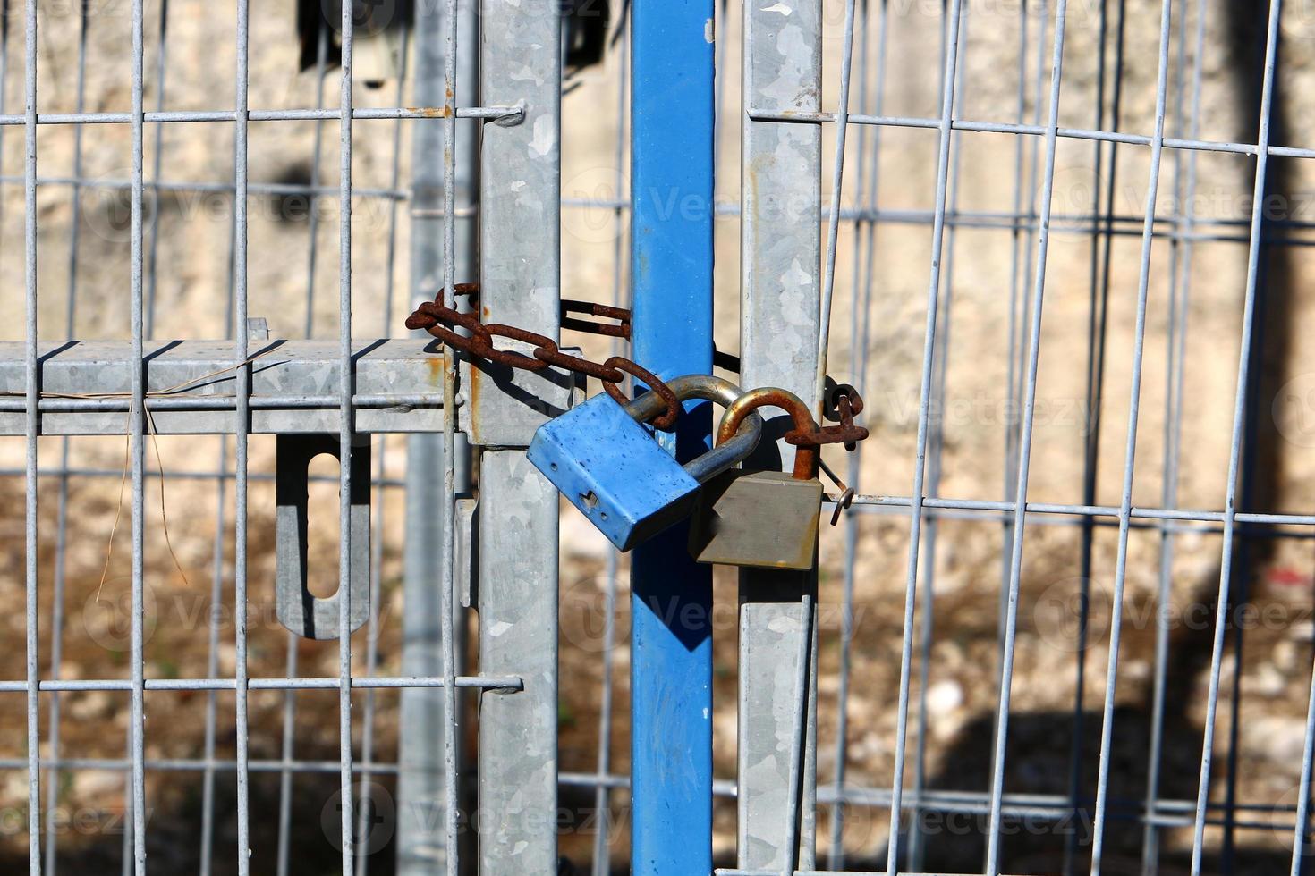 An iron padlock hangs on a closed gate photo