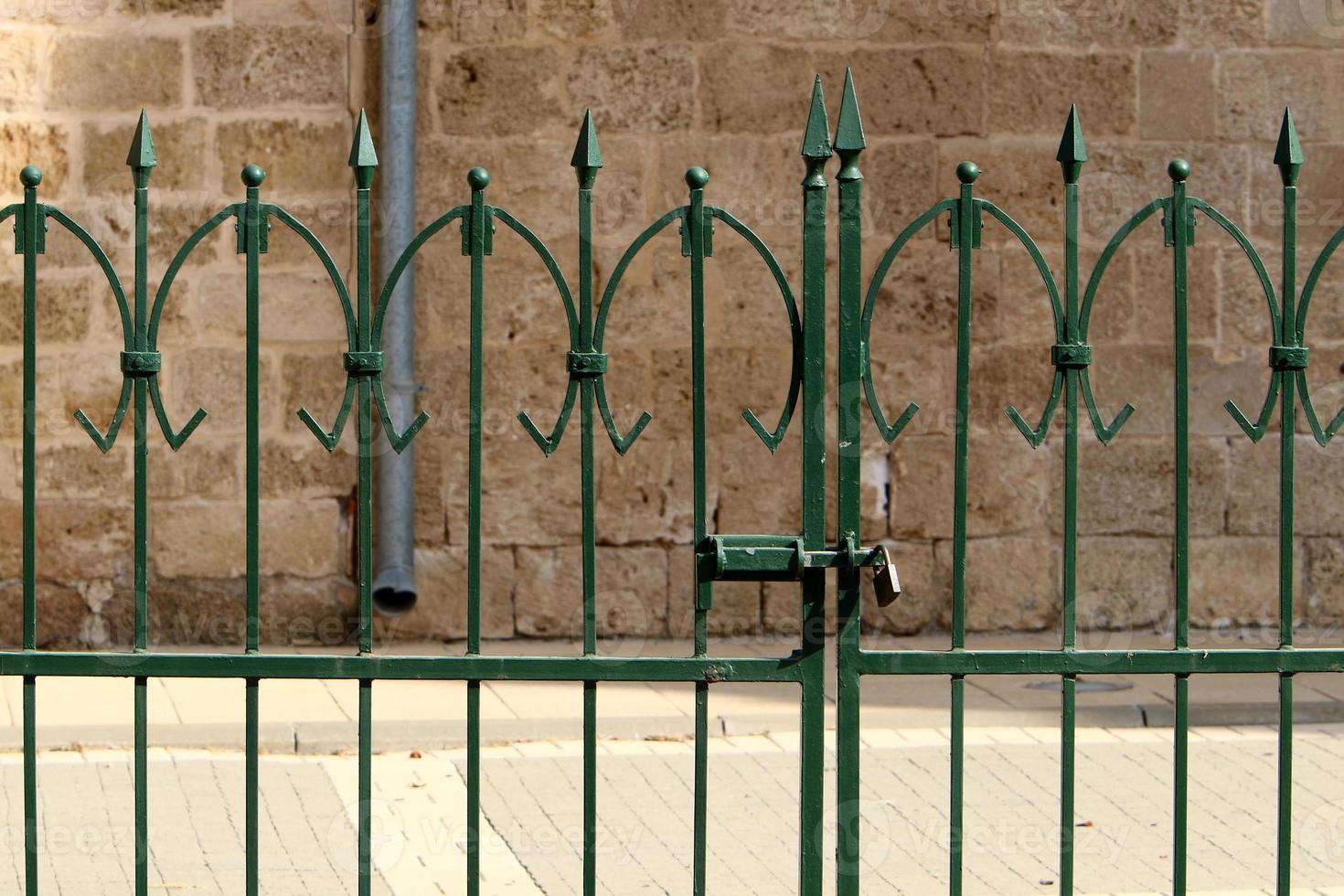 An iron padlock hangs on a closed gate photo
