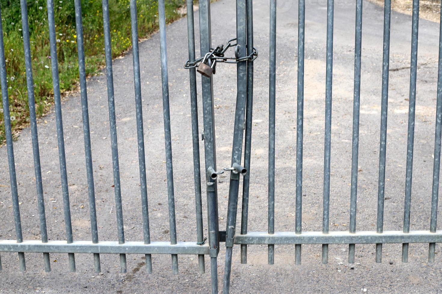 An iron padlock hangs on a closed gate photo