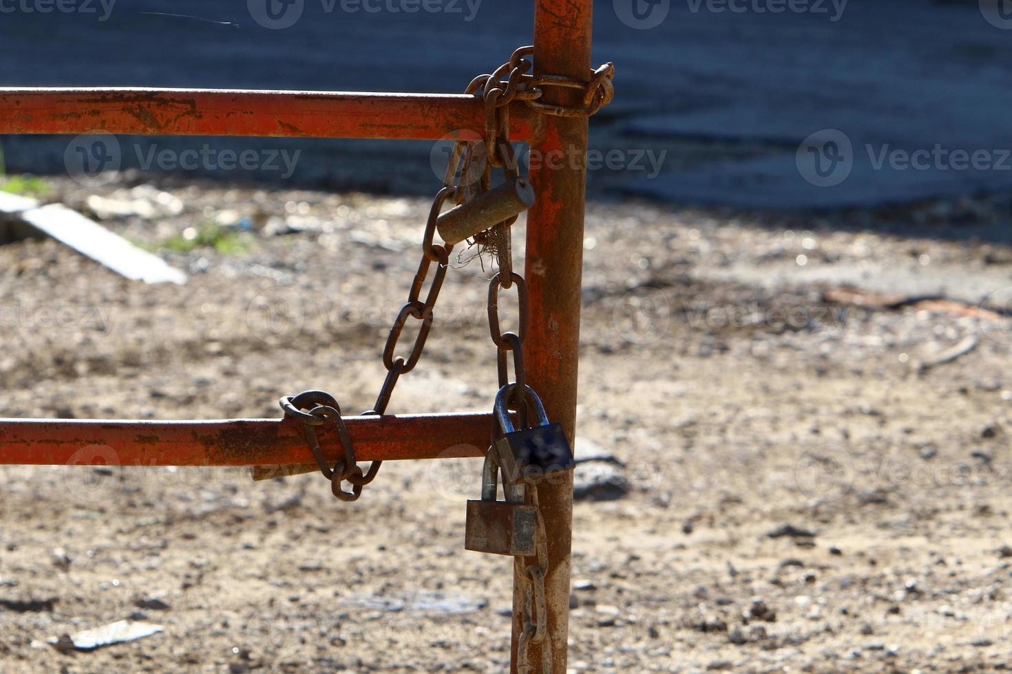 An iron padlock hangs on a closed gate photo