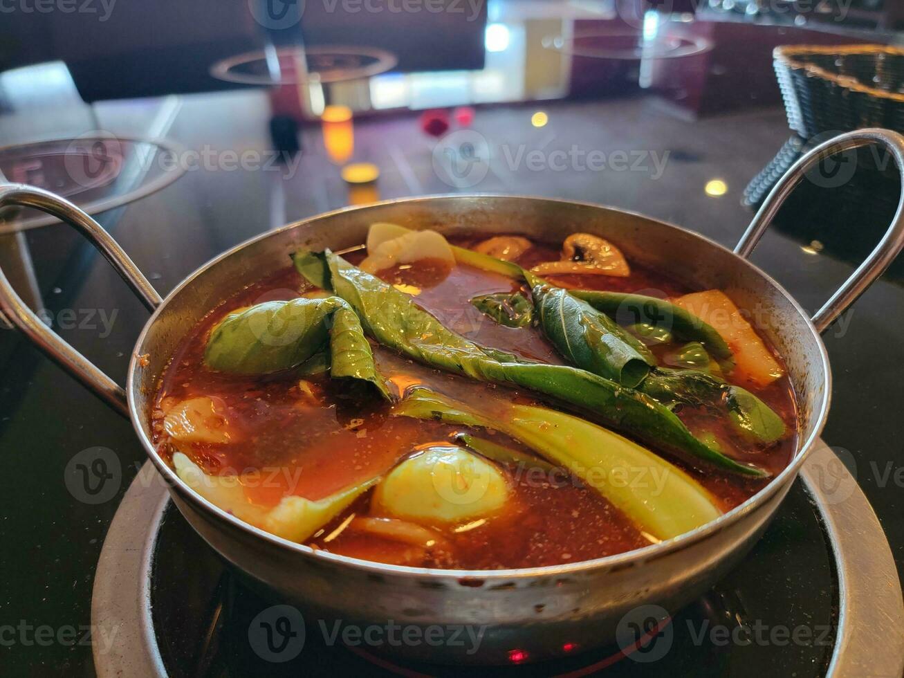 Chinese hot pot with spicy broth in bowl with vegetables photo