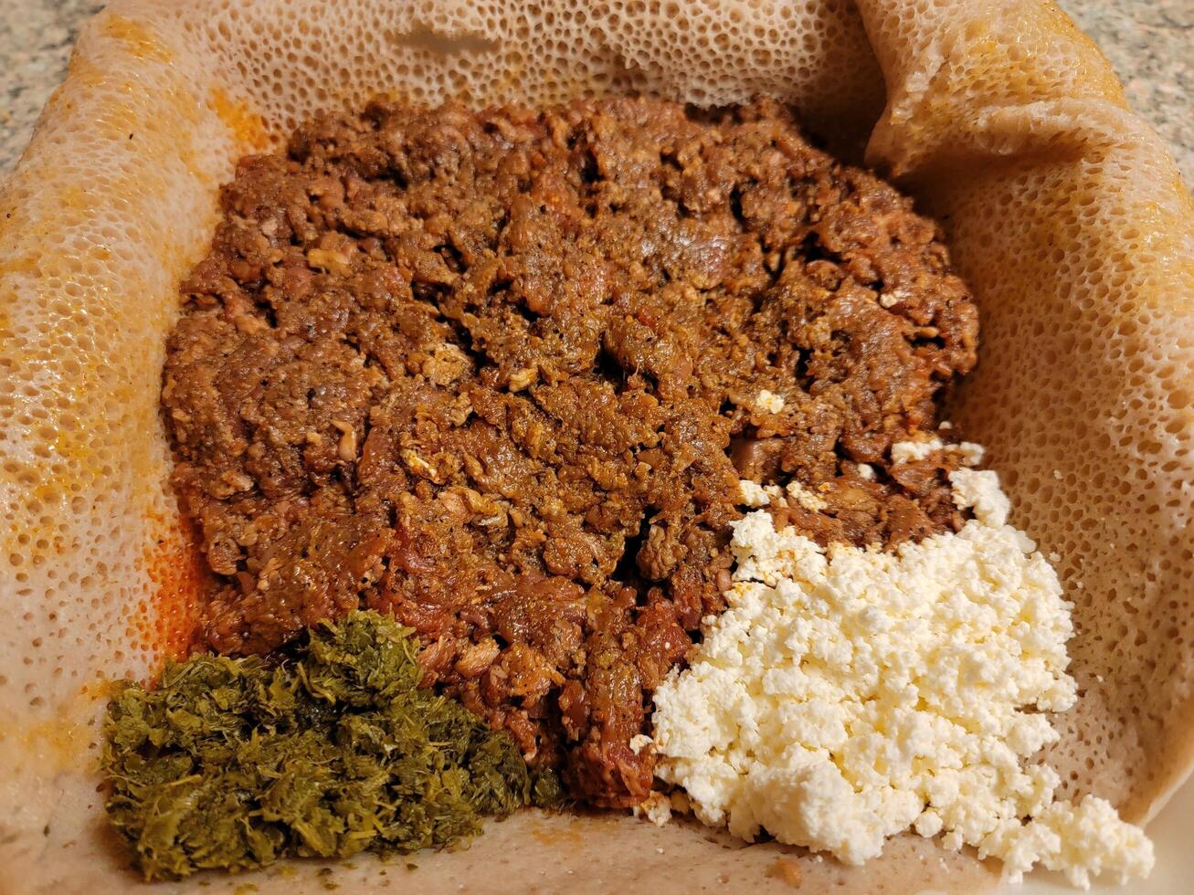 raw beef Ethiopian food called kitfo with bread and greens and cheese