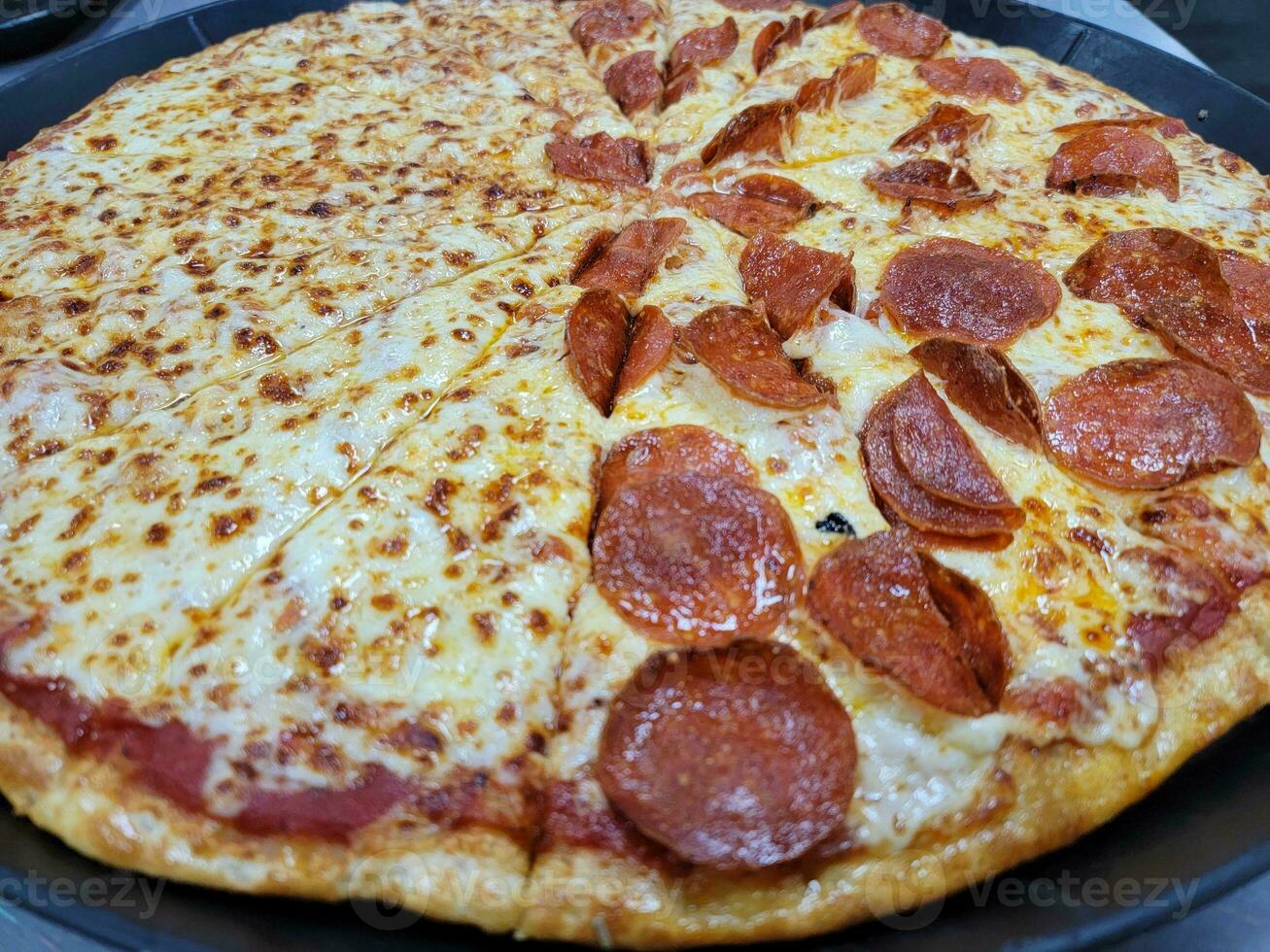 pizza de pepperoni en rodajas grandes con queso en bandeja foto