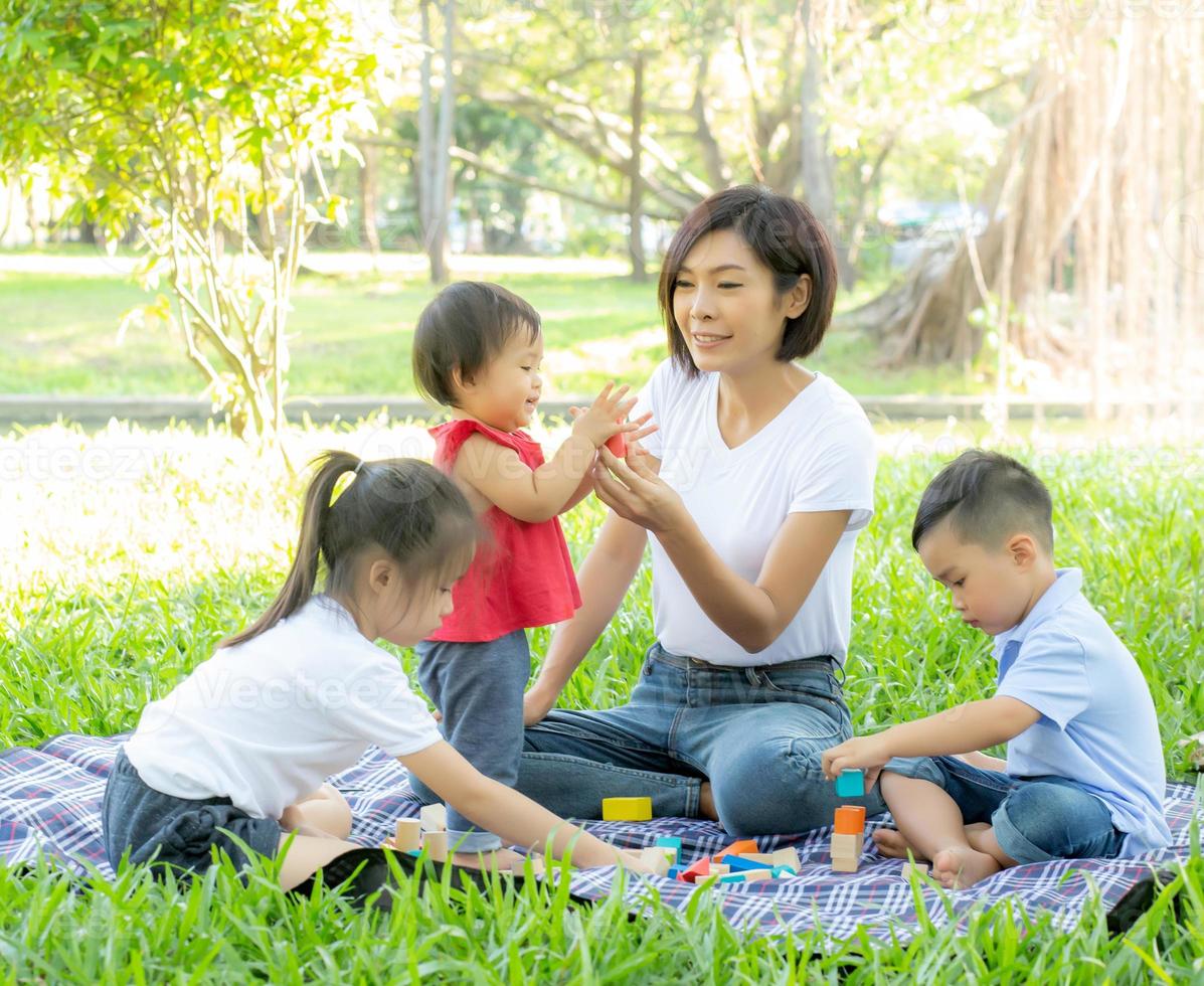 Beautiful young asian mom and daughter playing toy blocks for learning development happy and fun at park in summer, mother and kid cheerful activity together at garden in holiday, family concept. photo