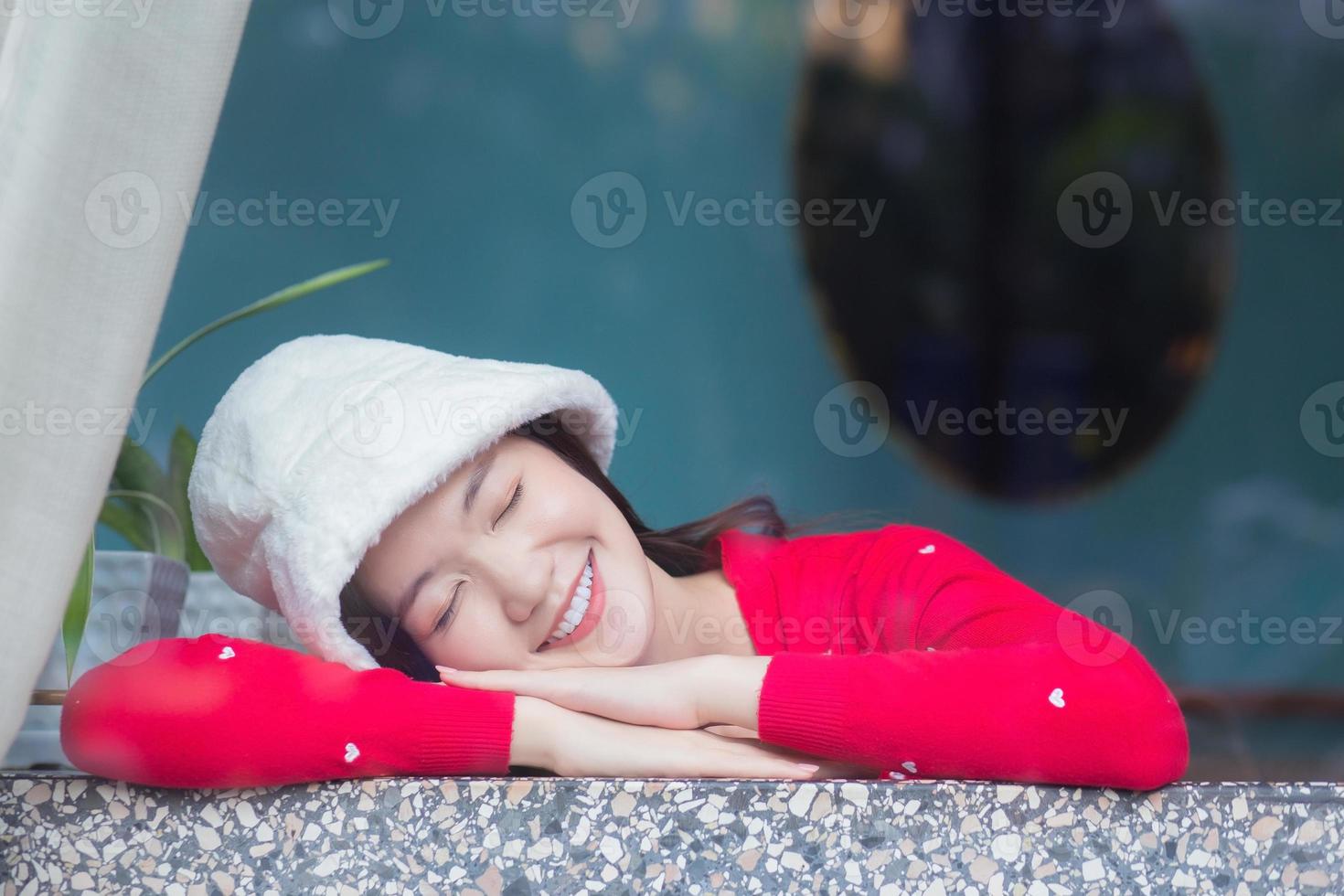 Portrait beautiful skin of Asian woman who wears red long sleeve cardigan and a cream hat smiles happily and sits with eyes closed. photo