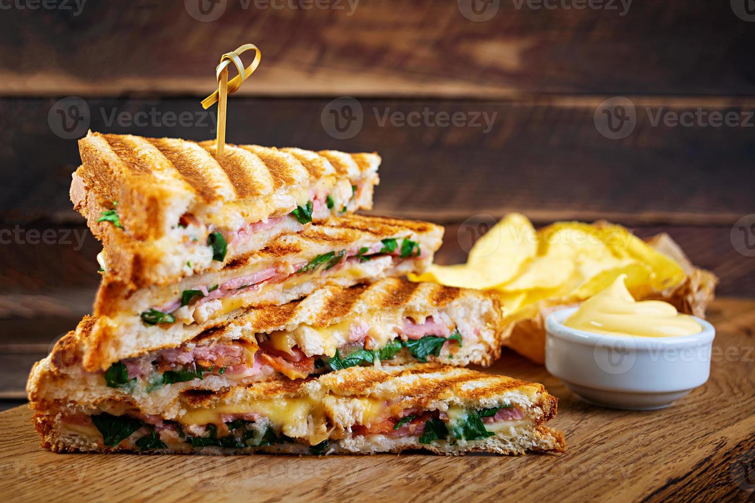 Club sandwich with ham, cheese, tomato, salad and chips photo