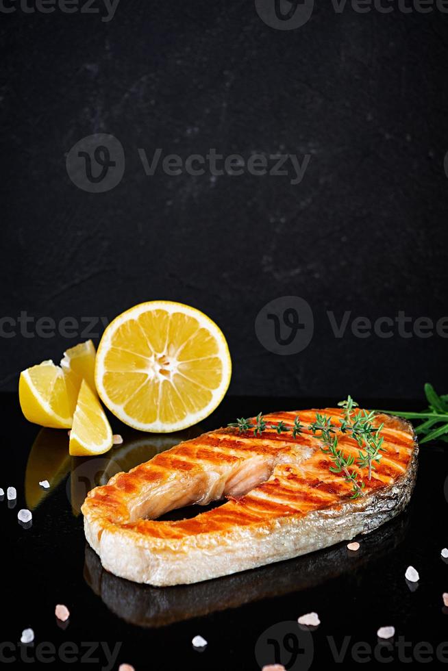 pescado salmón a la parrilla en tablero de piedra. salmón atlántico a la sal frito a la parrilla con limón foto