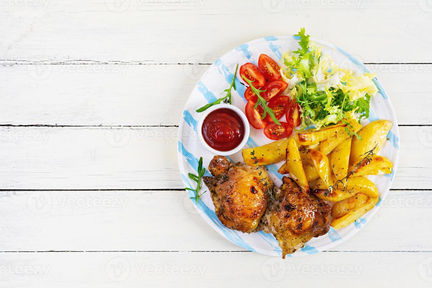 delicioso pollo al horno con patatas sobre fondo de madera. vista superior foto