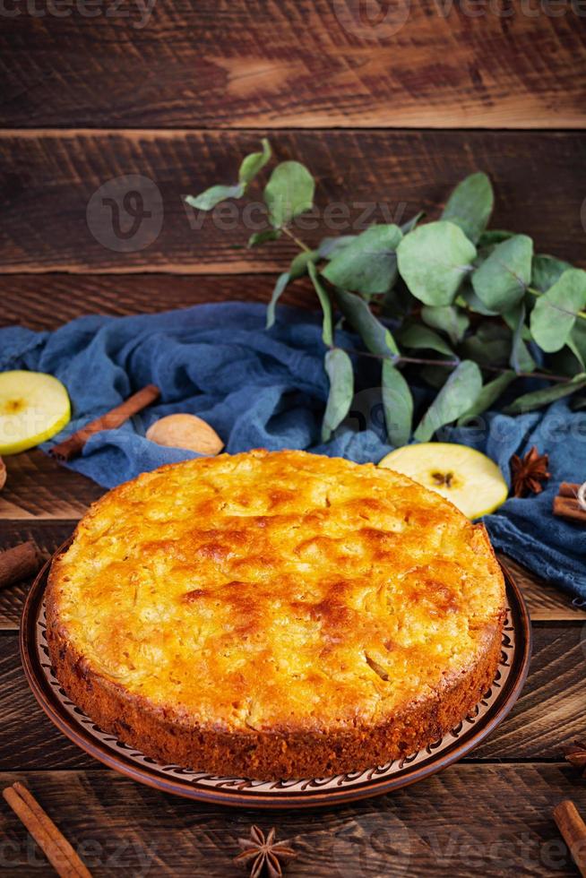 Delicious homemade apple pie on wooden background. Apple pie with ingredients, apples and cinnamon photo