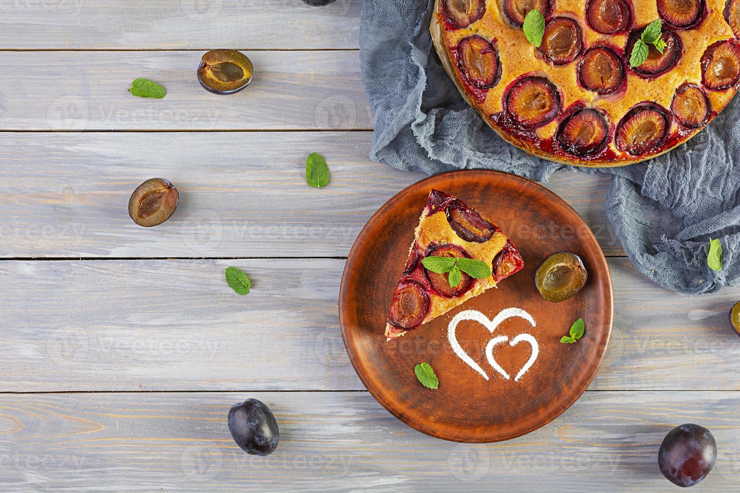 Delicious homemade plum pie on wooden background. Top view photo