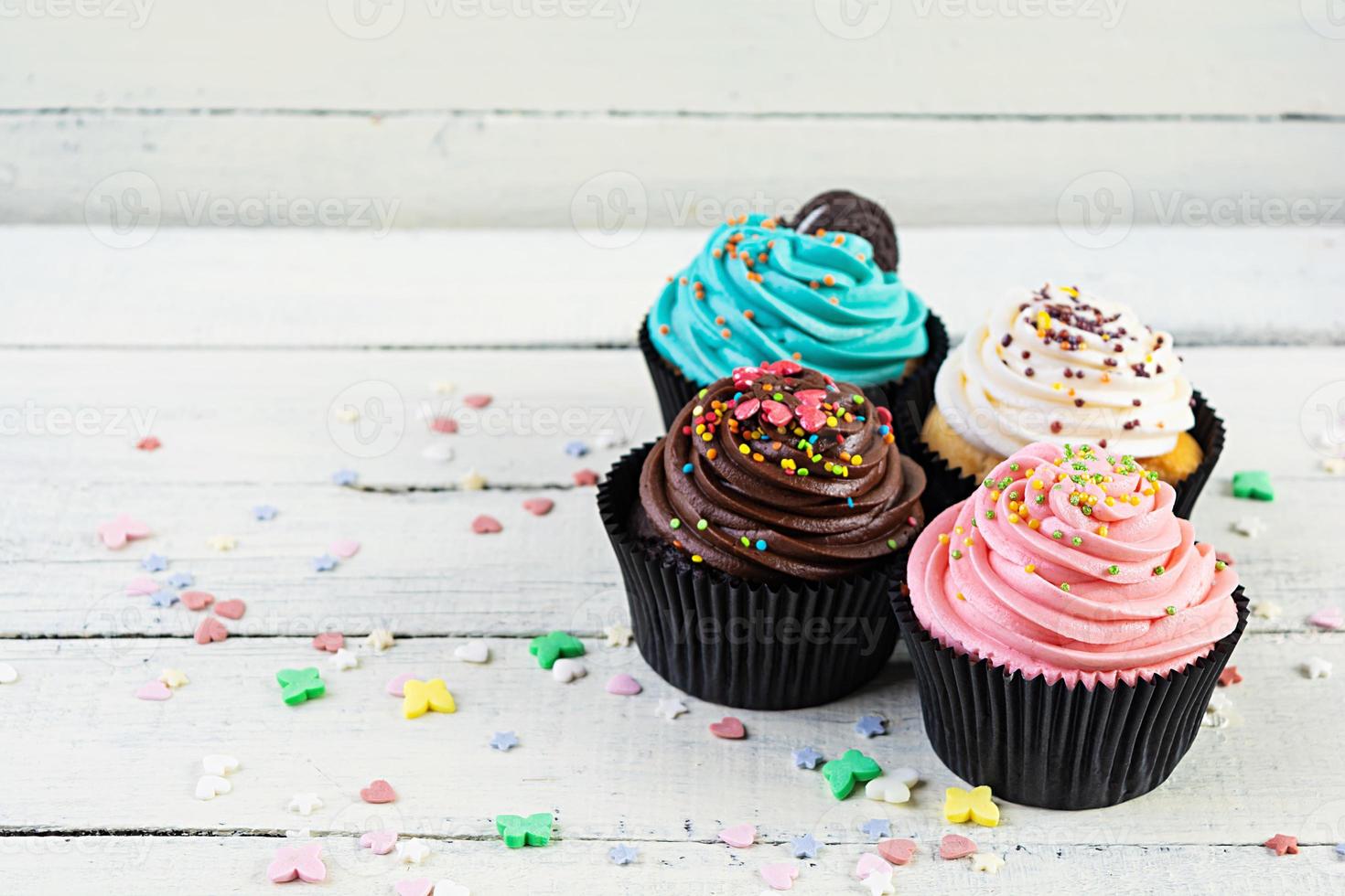 Tasty colorful cupcakes isolated on wooden background. Delicious cupcake photo