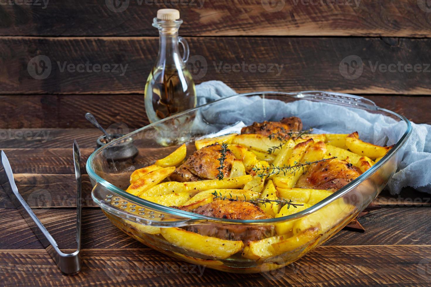Delicious baked chicken with potatoes on wooden background photo