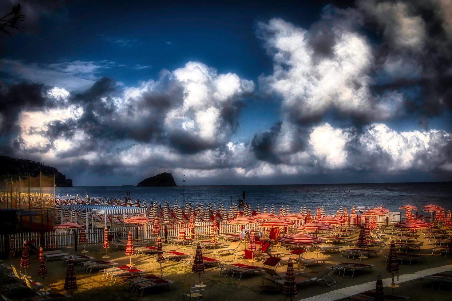 a beach with its deck chairs and umbrellas on a cloudy summer day. In Spotorno, on the western Ligurian coast photo