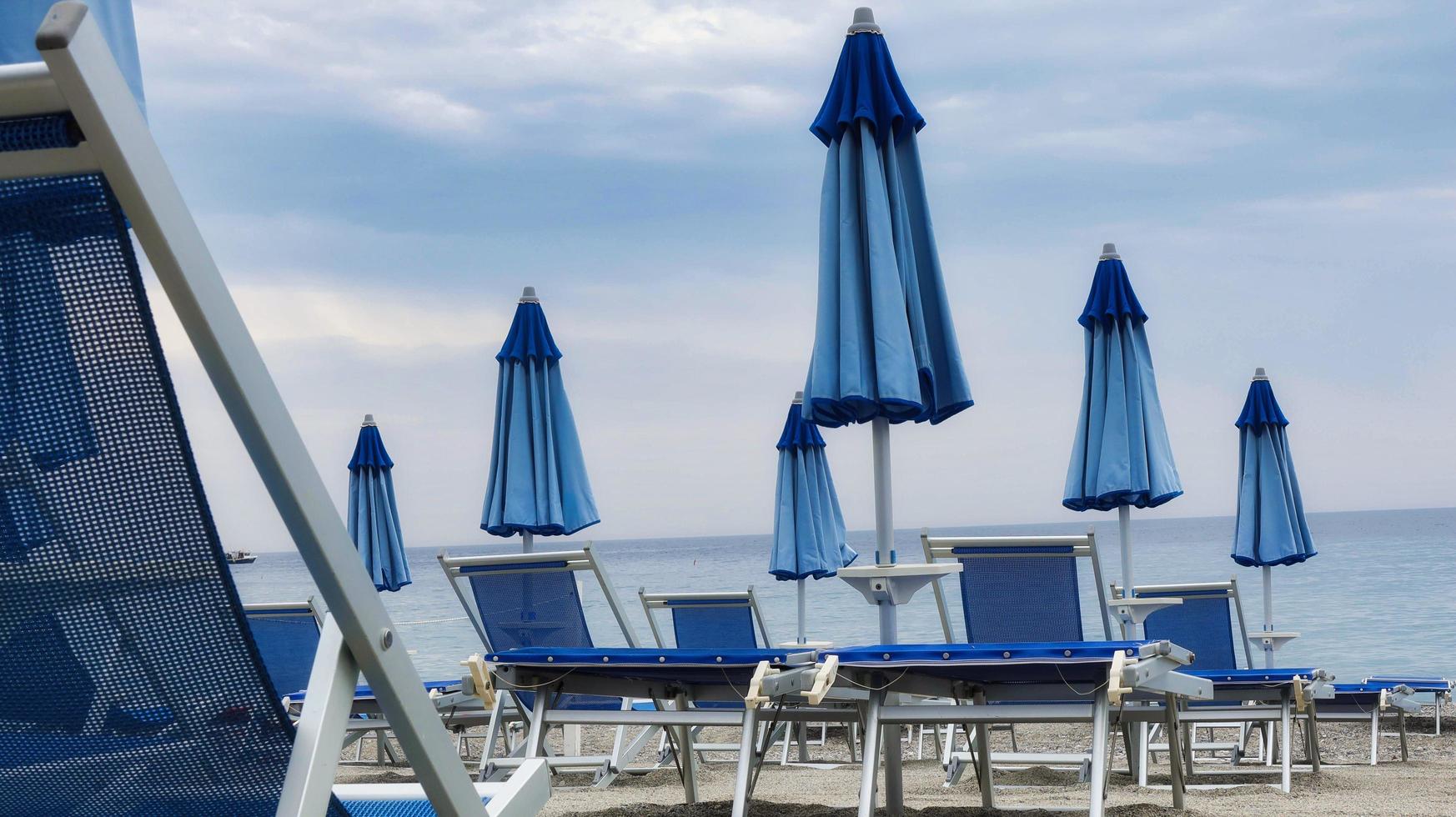 of deck chairs and umbrellas on the sand of the beach, during a summer day photo