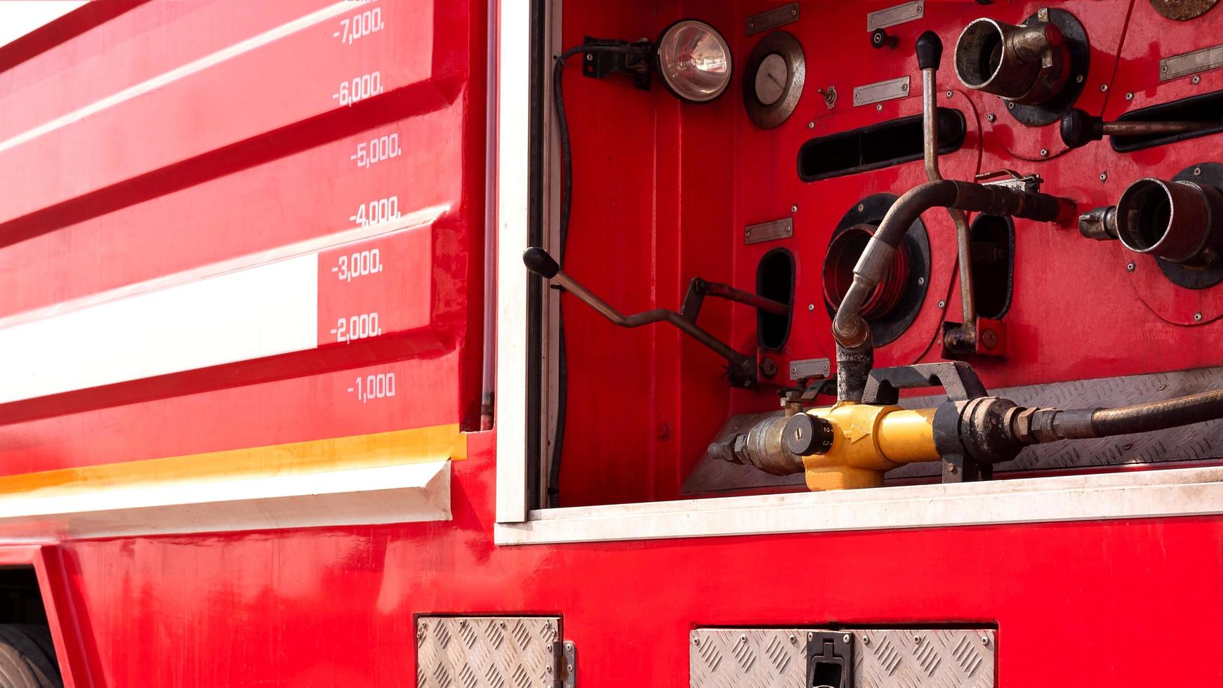 enfoque selectivo en la presión del indicador amarillo con palanca de válvula y bomba de seguridad contra incendios de alta presión en la vista lateral del camión de bomberos rojo foto