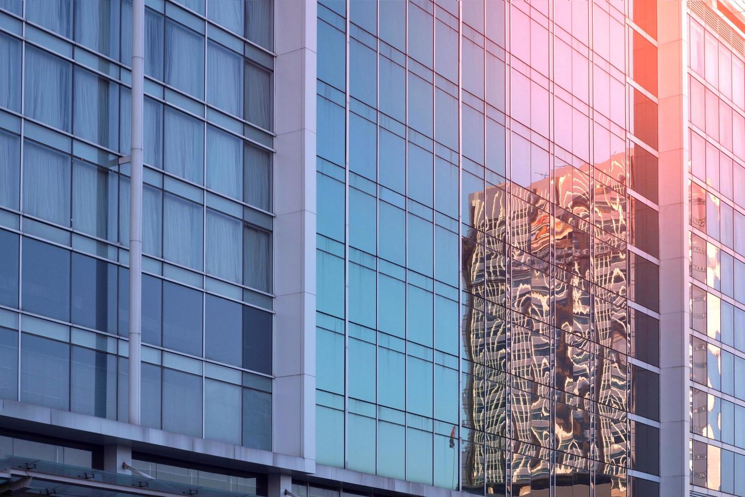 Low angle and side view of blue glass wall with reflection pattern of skyscraper and flare light on surface, architecture and buildings exterior design concept photo