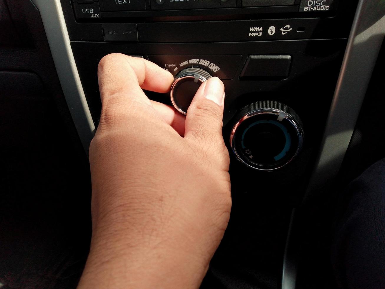 Man's hand controls the front of the car's fan air conditioner level. photo