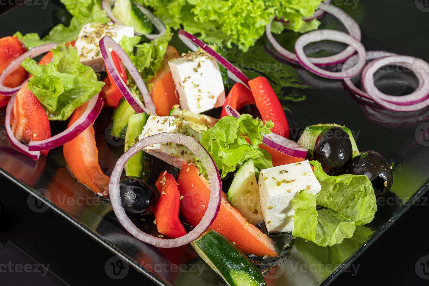 Greek salad with feta, tomatoes, olives and lettuce. On a dark background. photo