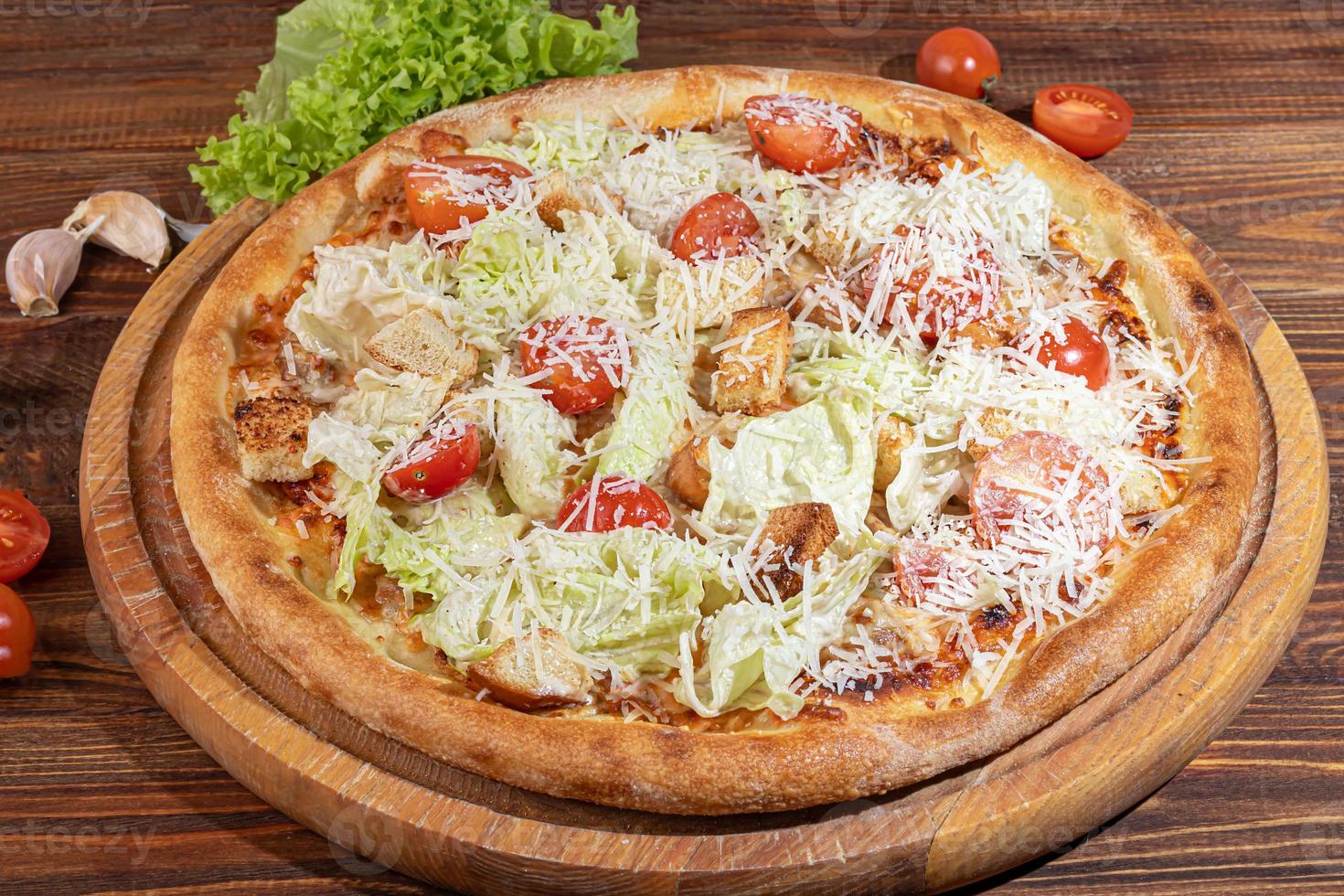 Pizza with bacon and cheese, herbs and cherry tomatoes. With mozzarella, shrimps and octopuses, mussels and other products on a wooden background. photo