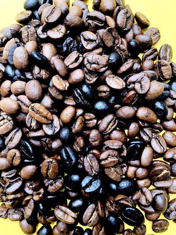 close up roasted coffee beans brown and dark seed variation on yellow background photo