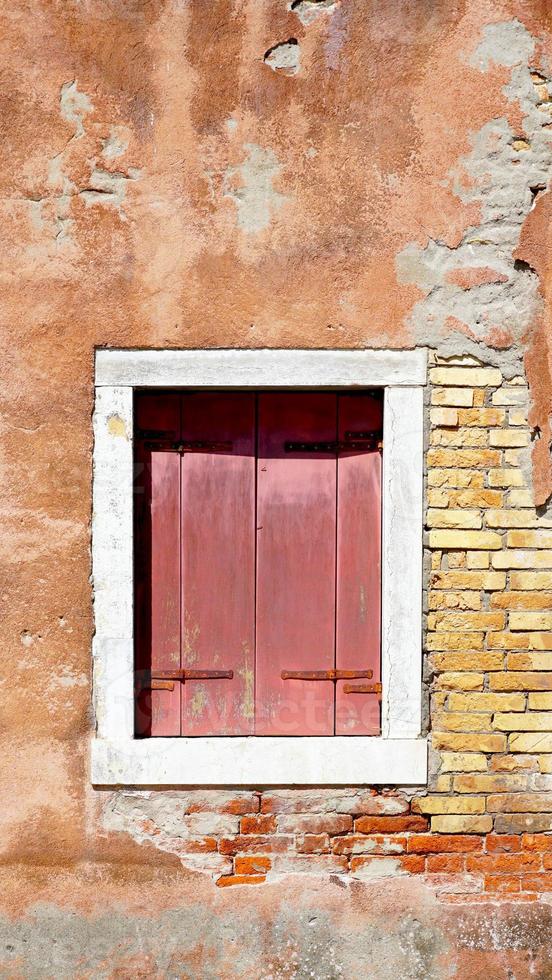 ventana de madera roja y antiguo muro de decadencia en venecia, italia foto