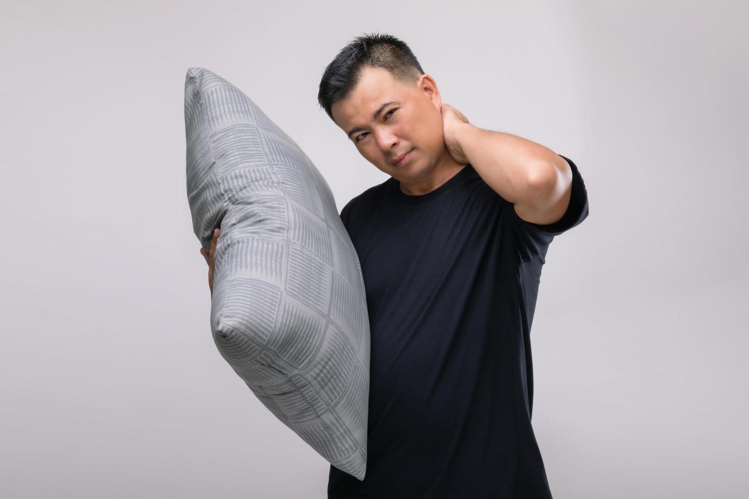 Neck aches concept, Portrait Asian man holding grey pillow and feeling tired or aches on his neck. Studio shot isolated on grey photo