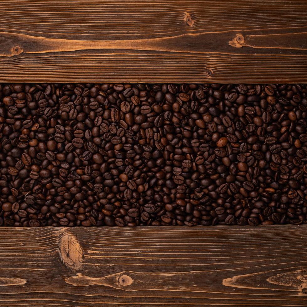 Roasted coffee beans and wooden texture. Top view brown coffee beans texture for backdrop and wallpaper use photo