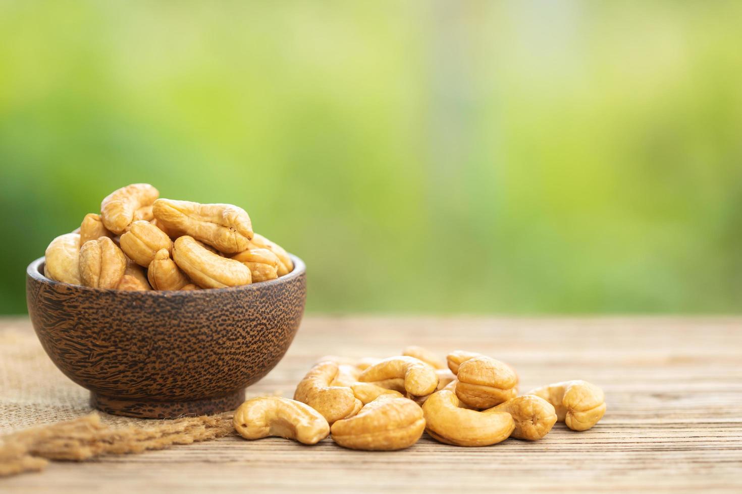 Pile of roasted cashew nut in bowl on the table. Blur green background photo