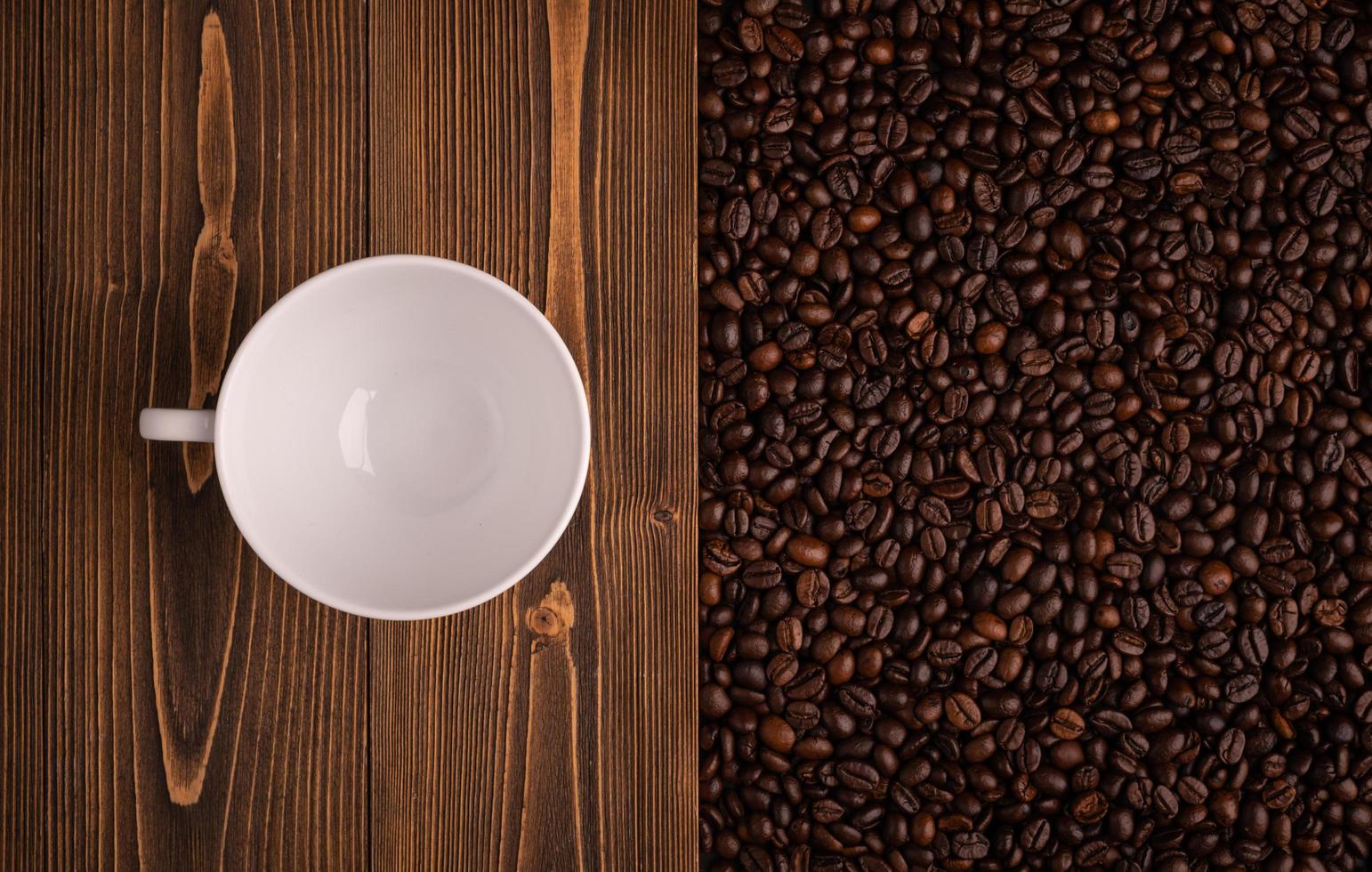 Roasted coffee beans and coffee cup on wooden texture. Top view brown coffee beans texture for backdrop and wallpaper use photo