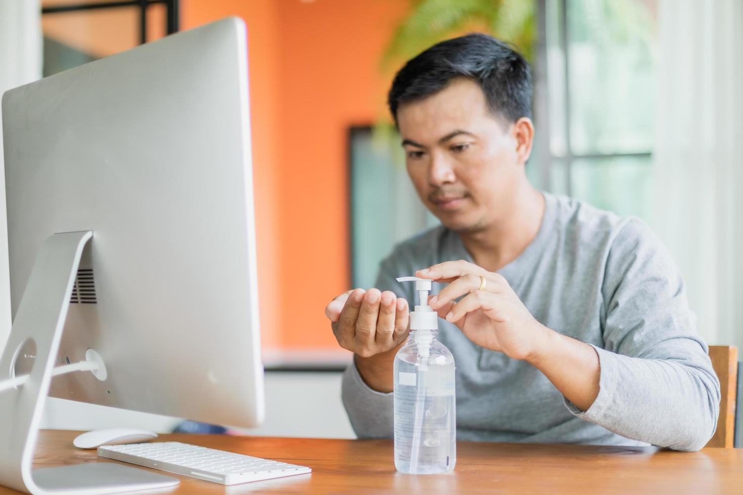 hombre usando gel desinfectante para manos para limpiar su mano, trabajar desde casa y un concepto saludable foto