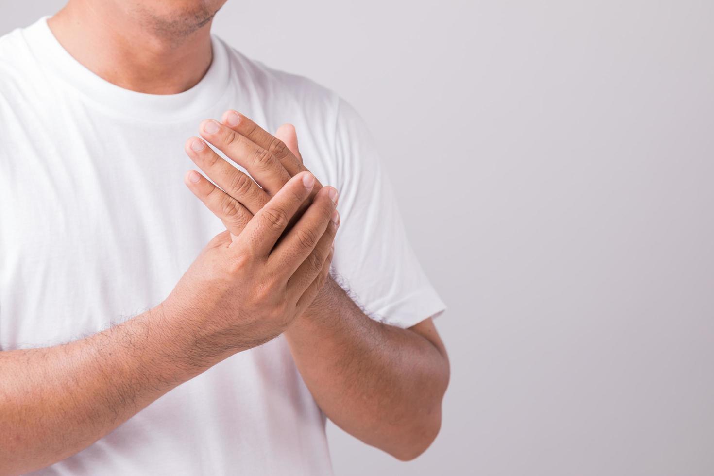 Close up man touching palm and feeling a pain. Studio shot isolated on grey background with copy space for text photo