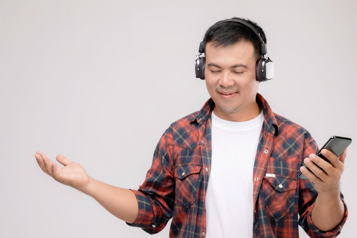 Portrait Asian man listening song or music from black headphone. Studio shot isolated on grey photo