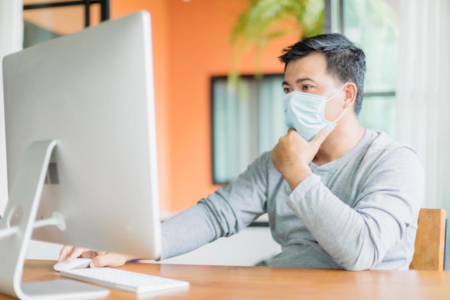 hombre con mascarilla preventiva y trabajando desde casa en situación de enfermedad por el virus de la corona. trabajo desde casa y concepto saludable foto