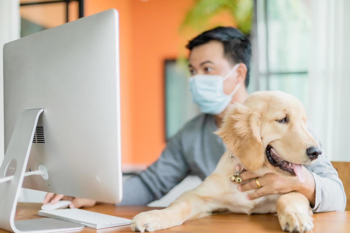 hombre con mascarilla preventiva y trabajando desde casa y cuidando a su perro en situación de enfermedad por el virus de la corona. trabajo desde casa y concepto saludable foto