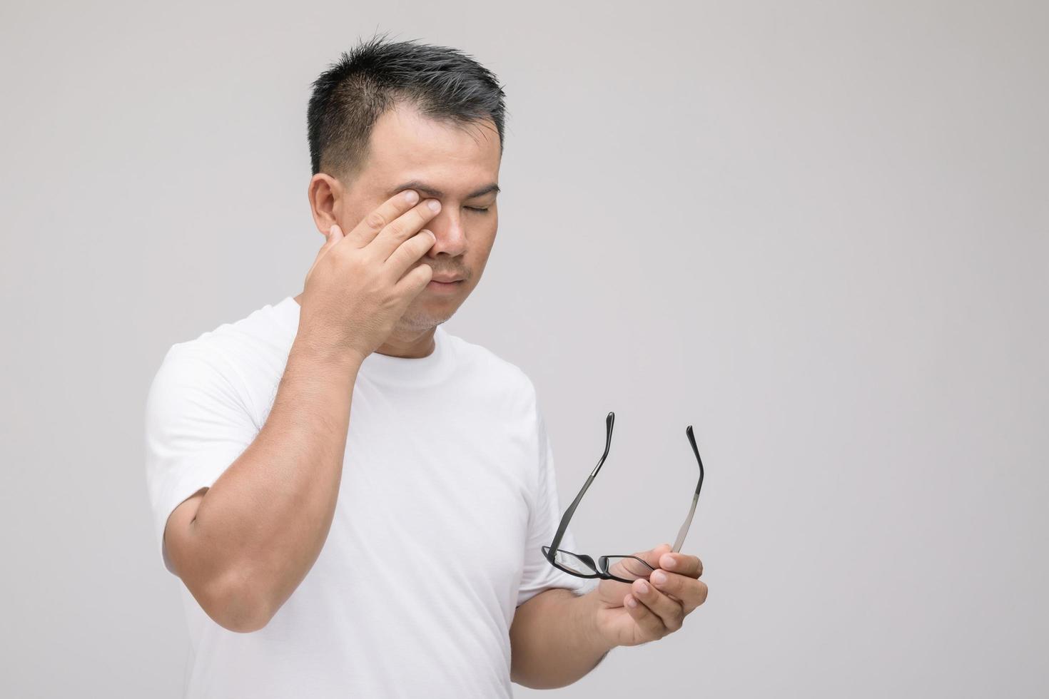 Eye irritation concept, Portrait of Asian man in posture of eye tired,  irritation or problem about his eye. Studio shot isolated on grey photo