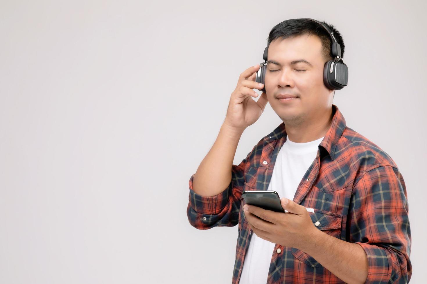 Portrait Asian man listening song or music from black headphone. Studio shot isolated on grey photo