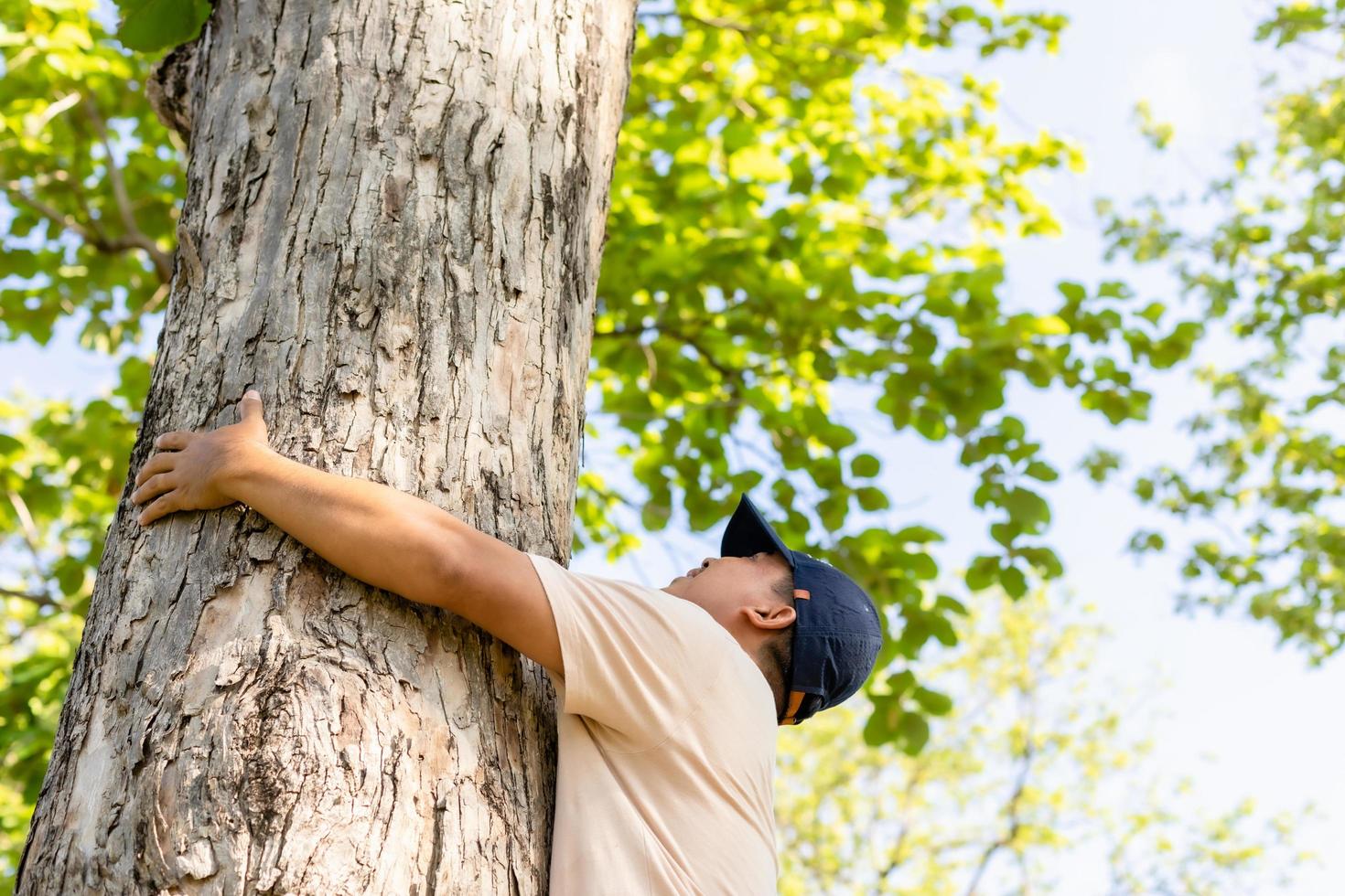 Asian man giving a hug on big teak tree hug. Love tree and nature or environment concept photo