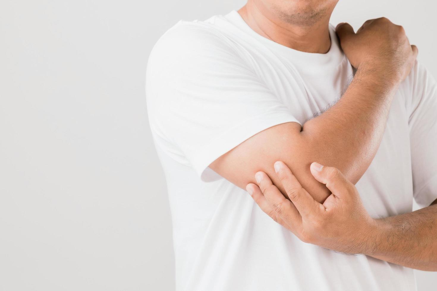 Close up man holding on elbow and feeling a pain. Studio shot isolated on grey background with copy space for text photo