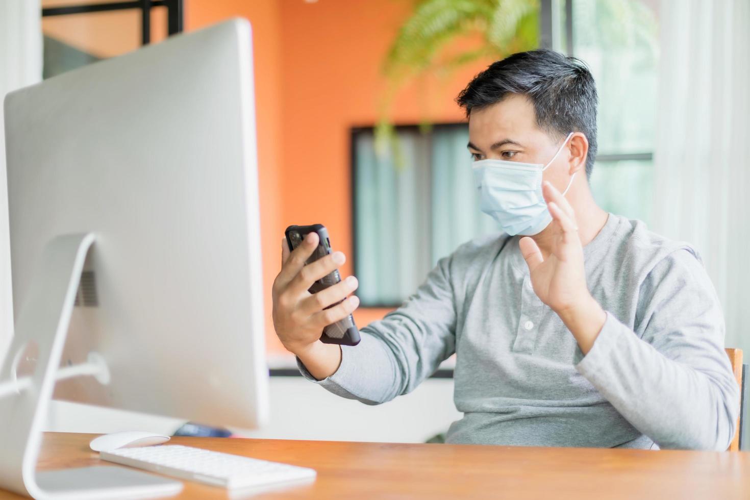 hombre con máscara preventiva y trabajando desde casa en situación de enfermedad por el virus de la corona. trabajo desde casa y concepto saludable foto